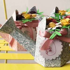 Boîtes pour petit cadeau ou chocolats en forme d'arrosoir avec un arrangement floral et une étiquette pour écrire un message.